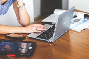 A laptop on a desk with a woman leaning over it researching the gender pay gap